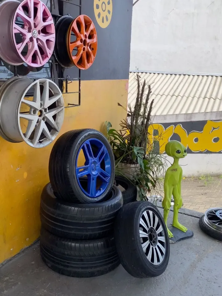 Rodas pintadas em rosa, laranja e azul expostas na oficina Amigos da Roda